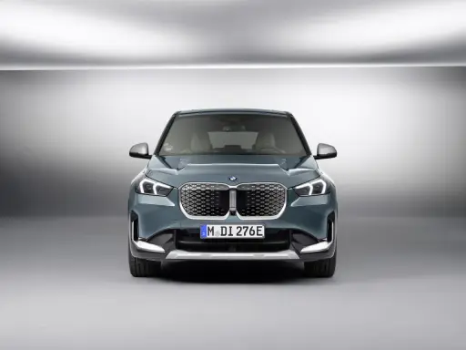 La BMW iX1, con la sua impressionante autonomia, si presenta frontalmente in un ambiente minimalista.