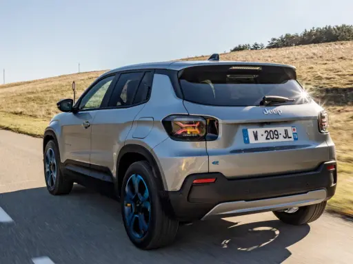 Jeep Avenger elettrica in corsa su strada panoramica, con cerchi blu e un'ottima autonomia per esplorare.