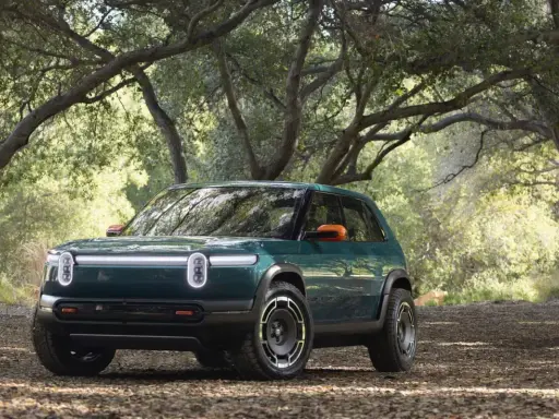 Un'avventura elettrica ti aspetta con la **Rivian R3X** verde bosco, pronta ad affrontare sentieri tra gli alberi.