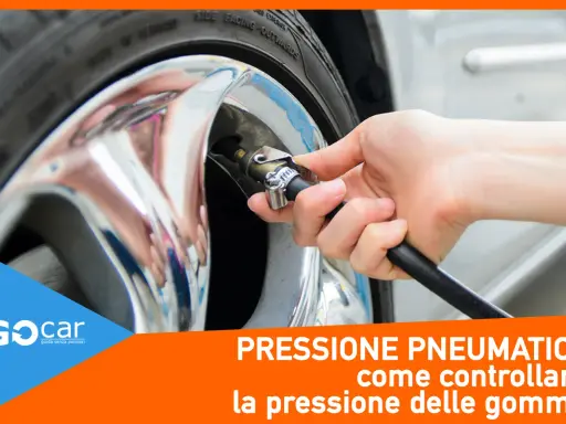 Controllo gomme auto: una mano collega il tubo di un compressore alla valvola di un pneumatico cromato. Essenziale per la sicurezza.