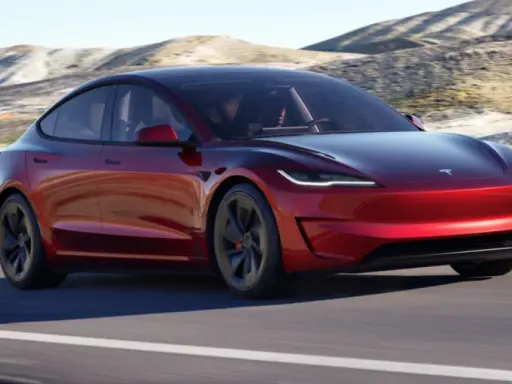 Tesla Model 3 rossa su strada panoramica. Il suo peso è ottimizzato per prestazioni elettriche.