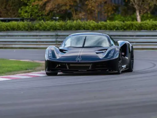 La Lotus Evija nera sfreccia su una pista, con un'aria di potenza e velocità.