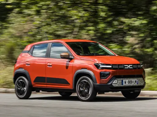Dacia Spring arancione in movimento, la sua compatta lunghezza la rende ideale per la città.