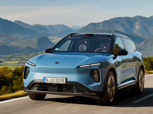 NIO ES6 blu sfreccia su una strada panoramica tra montagne verdi.