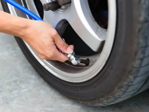 Mano che collega un tubo blu alla valvola per gonfiare gomme auto.