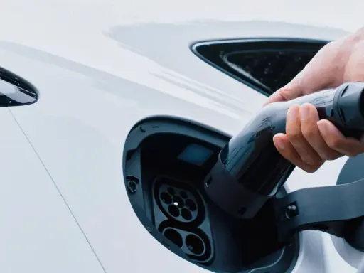 Mano inserisce la spina per trasformare l'auto in elettrica. Ricarica di un veicolo a zero emissioni.