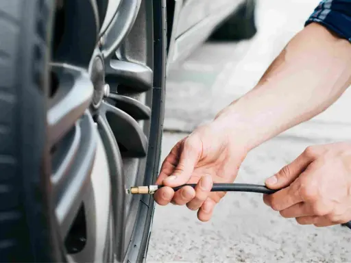 Mani che gonfiano uno pneumatico. Evitare pneumatici troppo gonfi conseguenze: usura irregolare e minore aderenza.