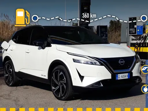 Nissan Qashqai e-POWER: potenza e autonomia per 360 km. L'auto è bianca, con tetto nero, e si trova vicino a una colonnina di ricarica.