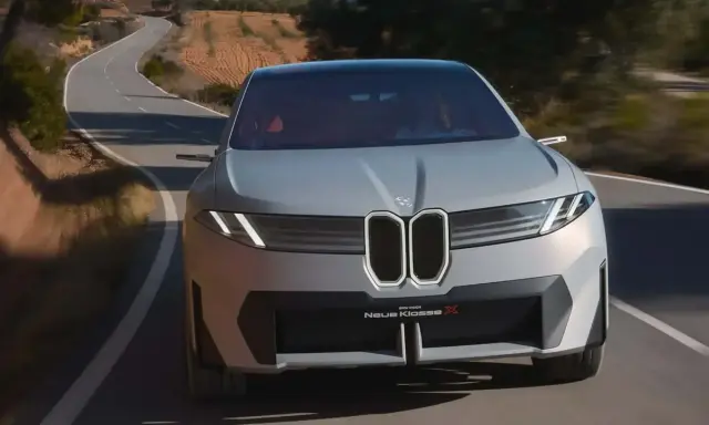 La BMW Neue Klasse X sfreccia su una strada tortuosa, un'icona di design futuristico.
