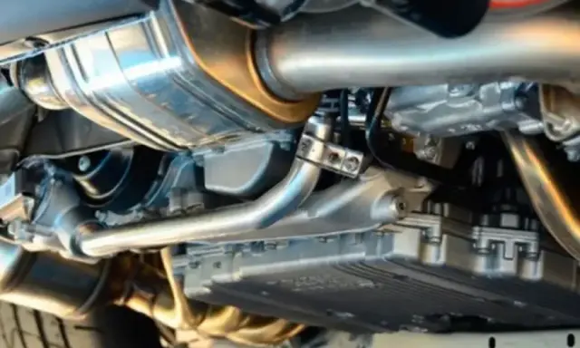Dettaglio del sistema di scarico di un'auto, con il tubo di scappamento auto lucido e altri componenti metallici.