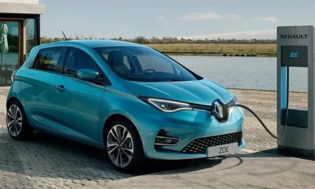 Renault Zoe, una delle auto elettriche più vendute, in carica vicino a un lago.
