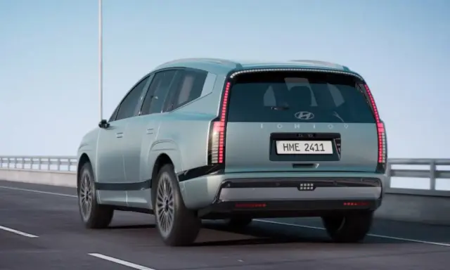 La nuova Ioniq 9, un SUV elettrico dal design futuristico, sfreccia su un'autostrada sotto un cielo azzurro.