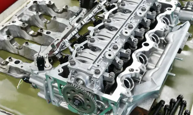 Parti di un motore rigenerato, con pistoni, valvole e ingranaggi in primo piano.