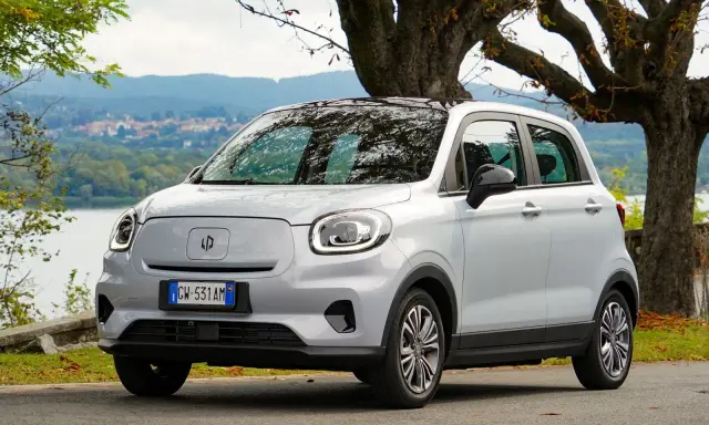 Leapmotor T03, un'auto elettrica grigia parcheggiata vicino a un lago, pronta per un viaggio con la sua eccellente autonomia.