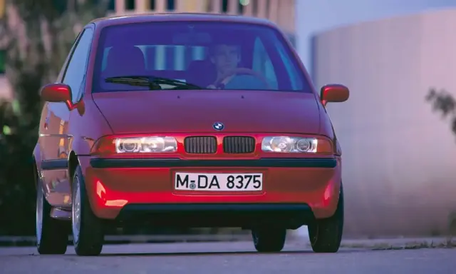 La BMW E1 rossa, un prototipo elettrico, si presenta con un design compatto e futuristico, pronta a sfrecciare nel traffico urbano.
