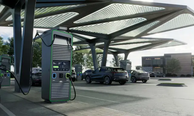 Moderne colonnine ricarica auto elettriche sotto una pensilina con pannelli solari. Diverse auto in carica.