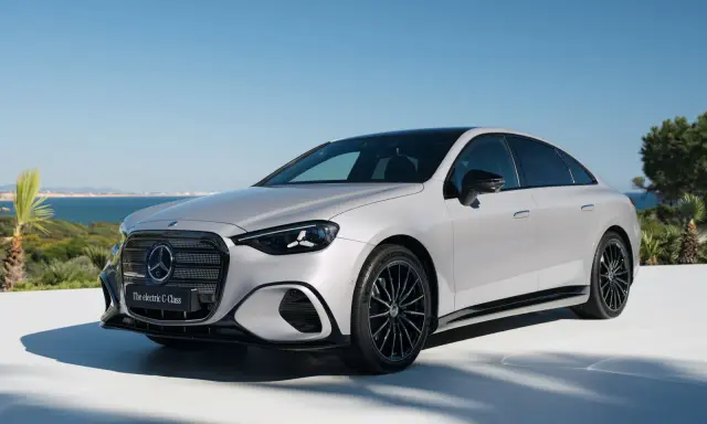 La Mercedes Classe C 2026, un'elegante berlina elettrica, si presenta con un design moderno e sportivo, con cerchi neri e uno sfondo marino.