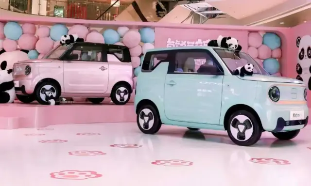 Due Geely Panda rosa e azzurra, circondate da palloncini e peluche di panda, in un allestimento a tema.