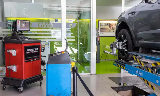 Attrezzatura per la convergenza auto in officina. Un'auto è sollevata su un ponte, con sensori applicati alla ruota.