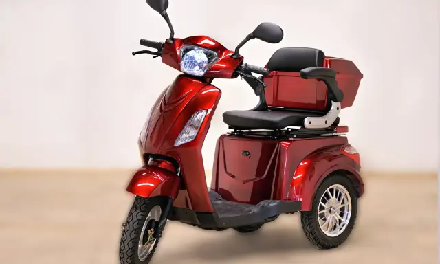 Un'auto elettrica a 3 ruote, rossa metallizzata, con sedile comodo e bauletto posteriore. Ideale per muoversi in città con stile e praticità.