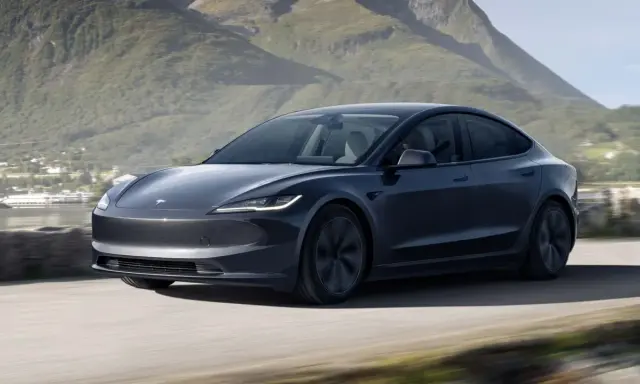 Tesla Model 3 grigia in movimento su strada panoramica, un'opzione tesla economica per esplorare la natura.