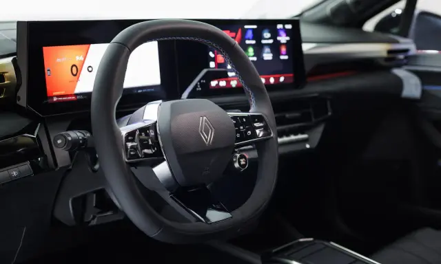 Volante e cruscotto digitale con schermi moderni, dettagli blu e logo Renault. Interni della nuova Clio 2026.