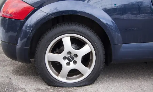 Ruota posteriore di un'auto blu con evidente perdita pressione pneumatici. Il coprimozzo riporta il logo "Borbet".