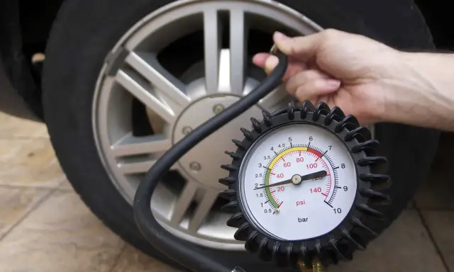 Controllo della pressione delle gomme auto con manometro. La lancetta indica circa 2 bar.