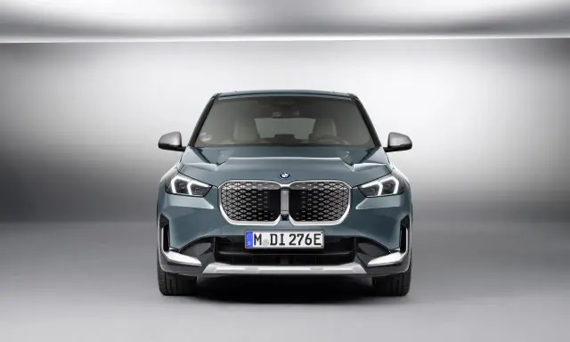 La BMW iX1, con la sua impressionante autonomia, si presenta frontalmente in un ambiente minimalista.