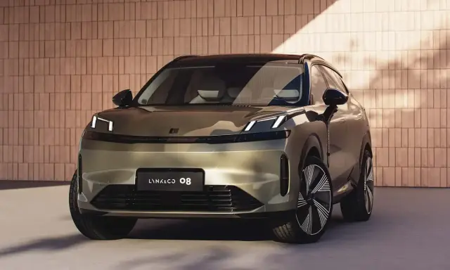 Lynk & Co 08, un SUV moderno con fari a LED distintivi, si presenta con un design audace su uno sfondo di mattoni.