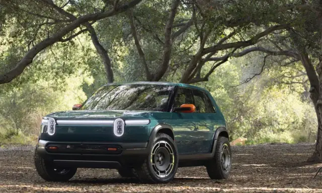 Un'avventura elettrica ti aspetta con la **Rivian R3X** verde bosco, pronta ad affrontare sentieri tra gli alberi.