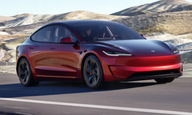 Tesla Model 3 rossa su strada panoramica. Il suo peso è ottimizzato per prestazioni elettriche.