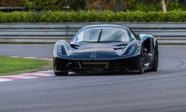 La Lotus Evija nera sfreccia su una pista, con un'aria di potenza e velocità.