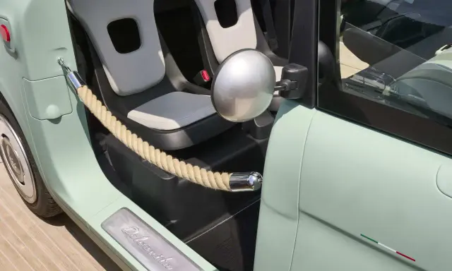 Interni Fiat Topolino: sedili chiari, corda decorativa e logo "Dolcevita" sulla soglia.