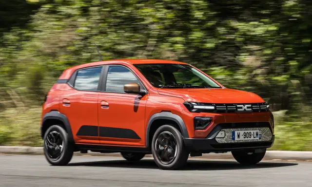 Dacia Spring arancione in movimento, la sua compatta lunghezza la rende ideale per la città.
