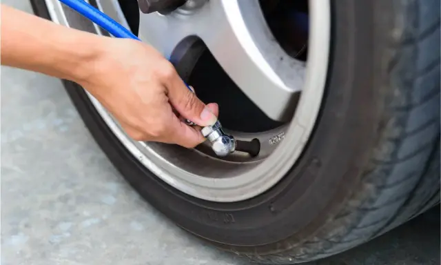 Mano che collega un tubo blu alla valvola per gonfiare gomme auto.