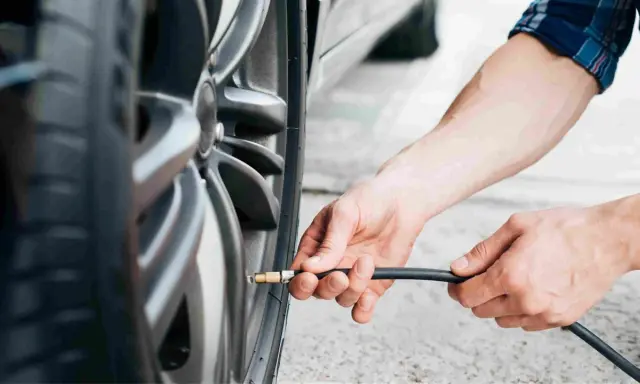 Mani che gonfiano uno pneumatico. Evitare pneumatici troppo gonfi conseguenze: usura irregolare e minore aderenza.