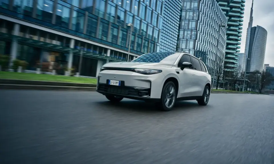 La Leapmotor C10 REEV sfreccia su strada, circondata da moderni grattacieli.
