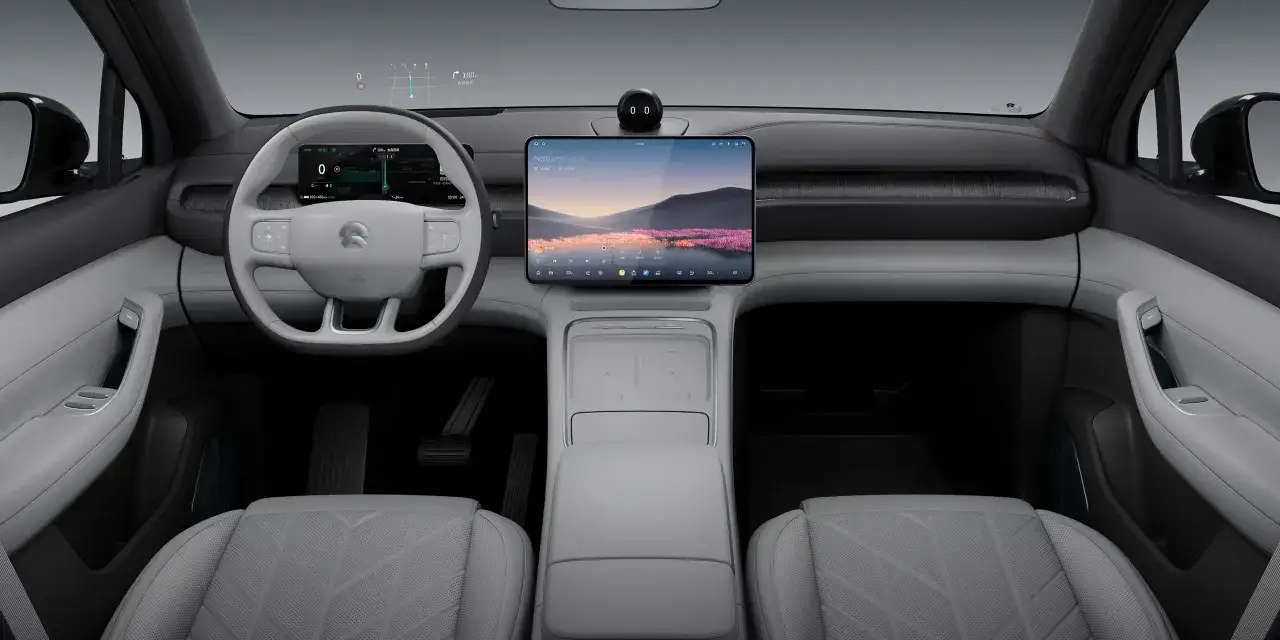 Interno moderno di un'auto elettrica NIO ES6 con ampio display centrale e cruscotto digitale.