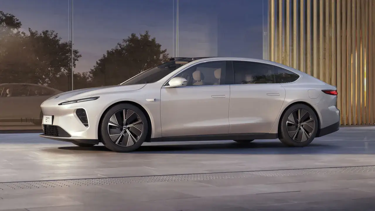 Nio ET7, un'elegante berlina elettrica color perla, parcheggiata davanti a un edificio moderno con pannelli di legno.