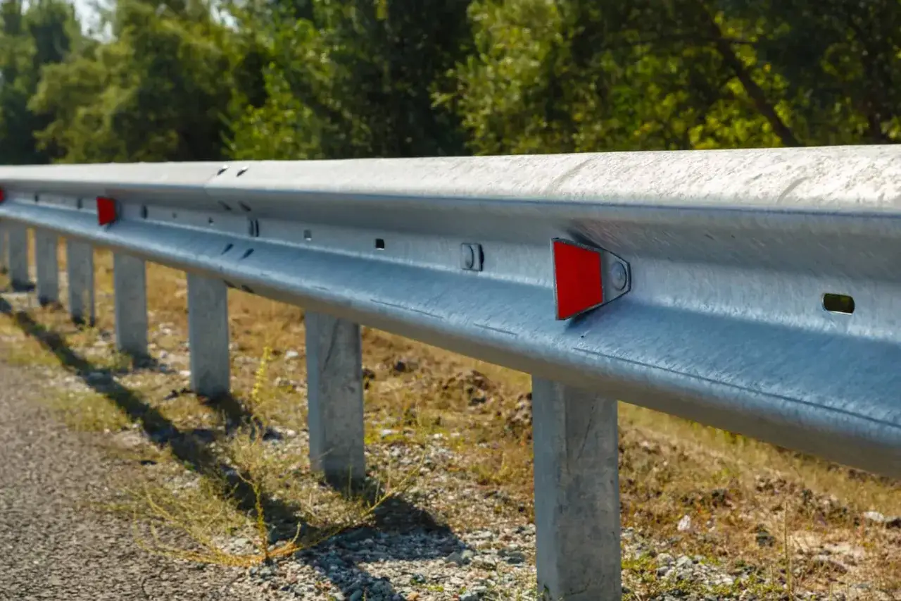 Guardrail con catadiottri rossi, elementi riflettenti che aiutano a segnalare la strada di notte.