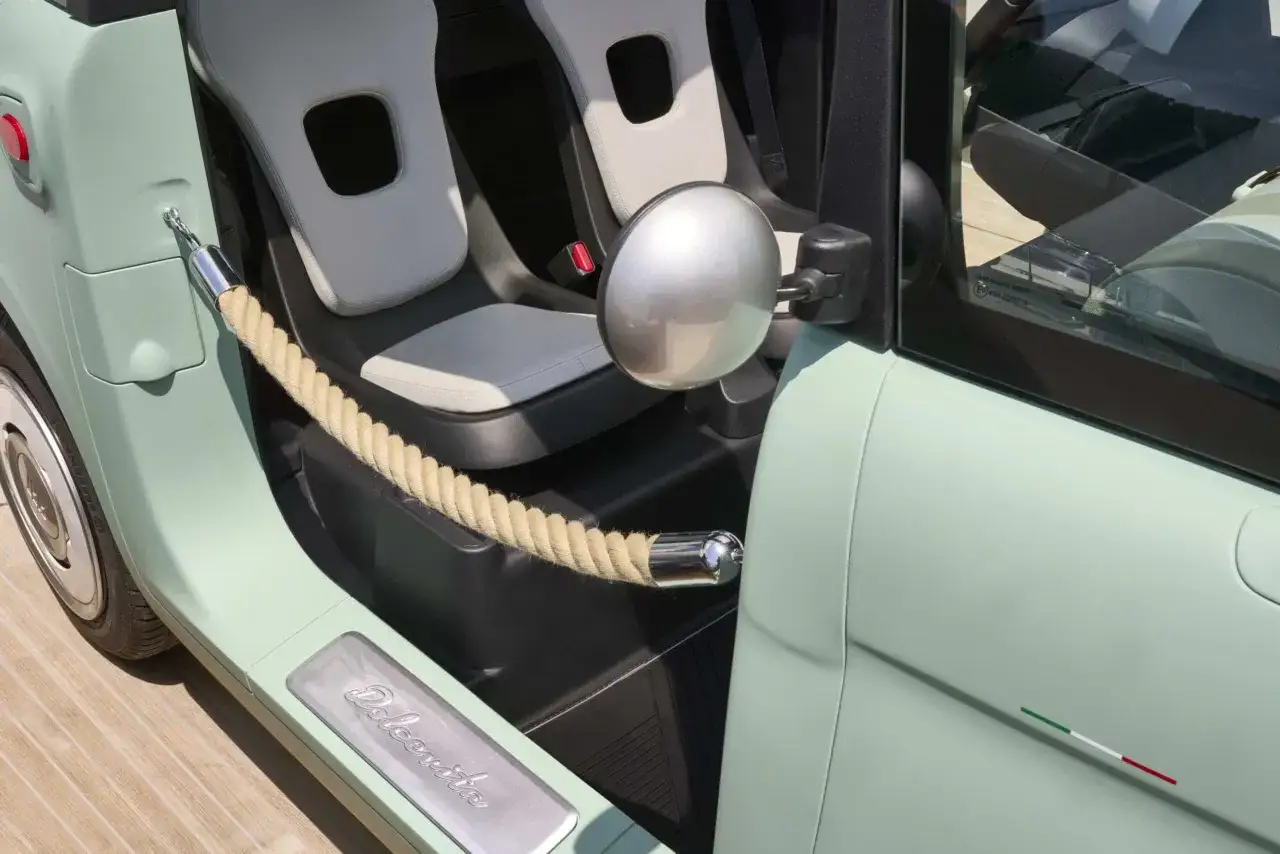 Interni Fiat Topolino con sedili chiari, specchietto tondo e corda decorativa. La scritta 