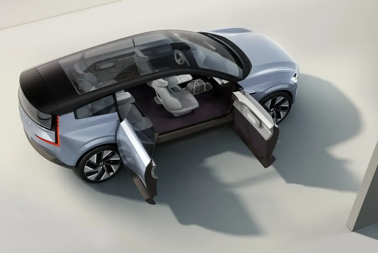 Interno minimalista del Volvo EX90, con porte aperte e tetto panoramico in vetro.