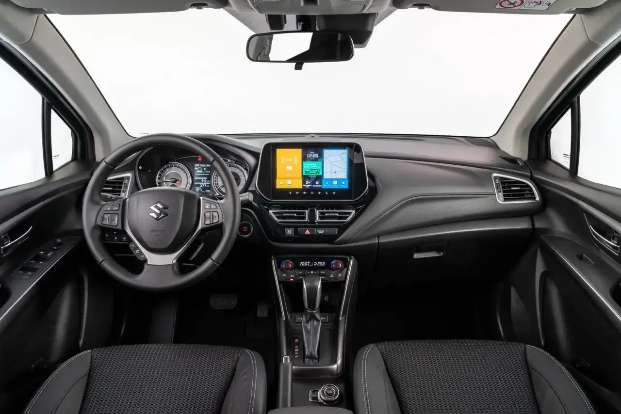 Interno della Suzuki S-Cross 2026: volante, cruscotto digitale, schermo infotainment con navigatore e climatizzatore bizona.