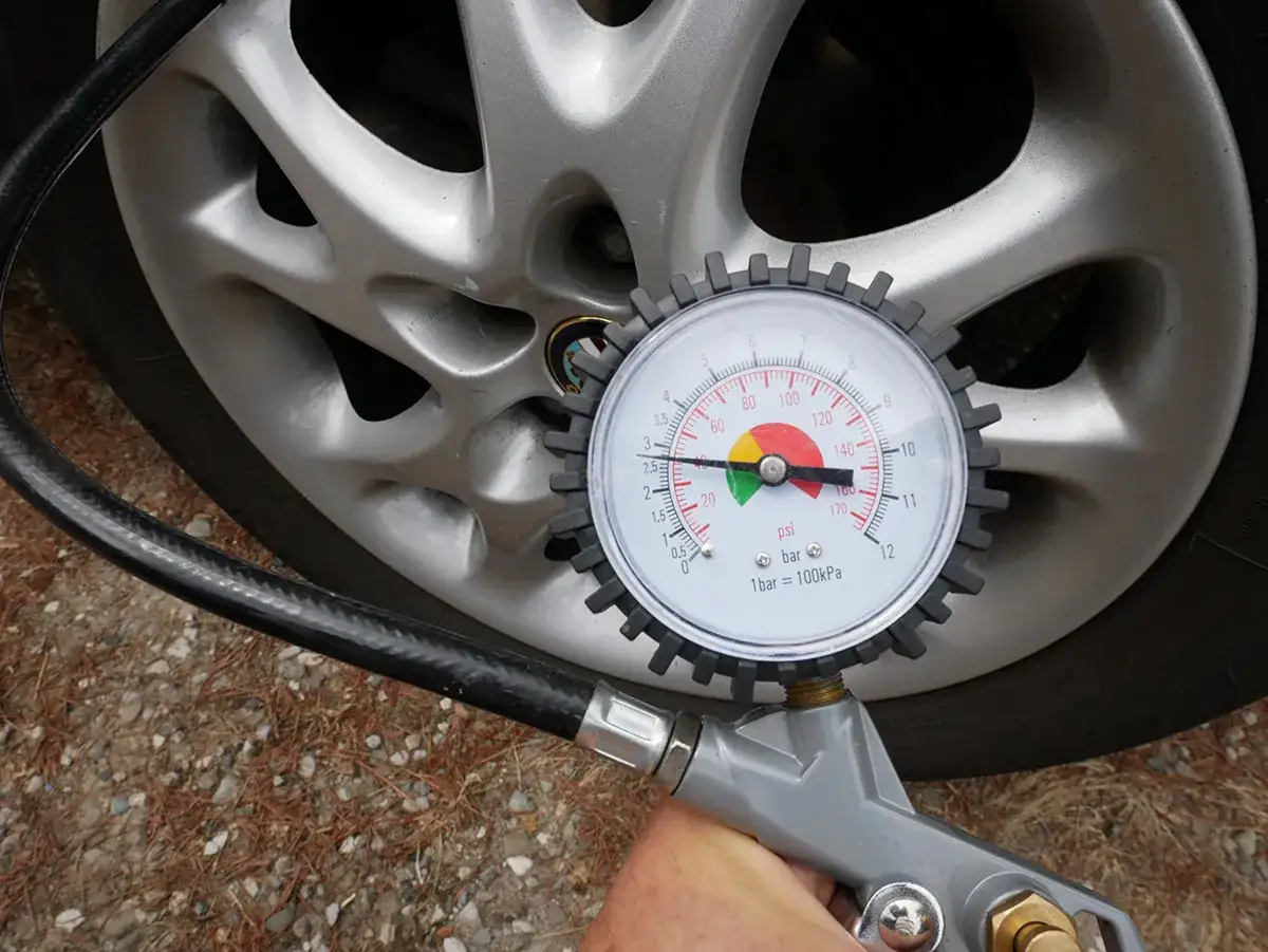 Controllo gomme auto: un manometro indica la pressione di un pneumatico, con l'ago nella zona verde.