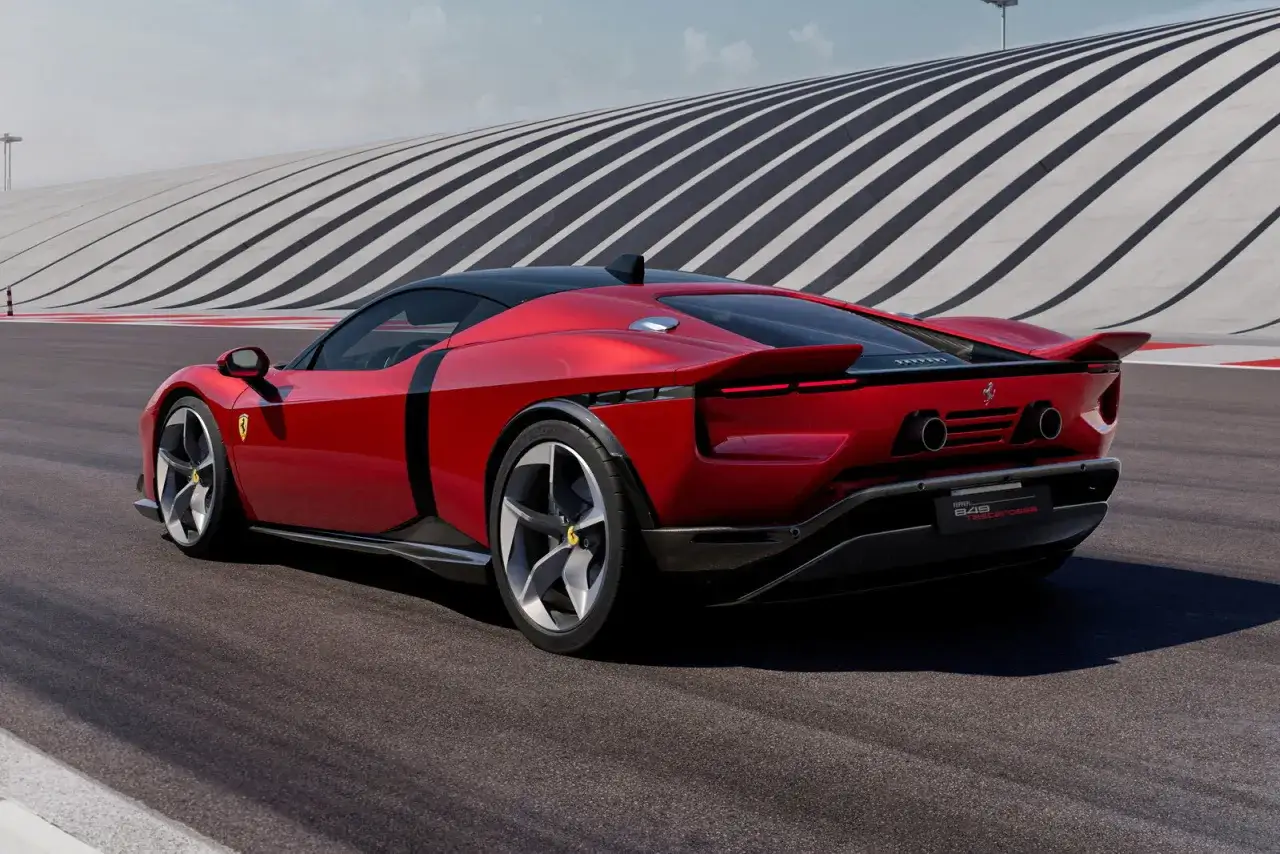 Iconica Ferrari 849 Testarossa rossa fiammante sfreccia su un circuito con sfondo a strisce.
