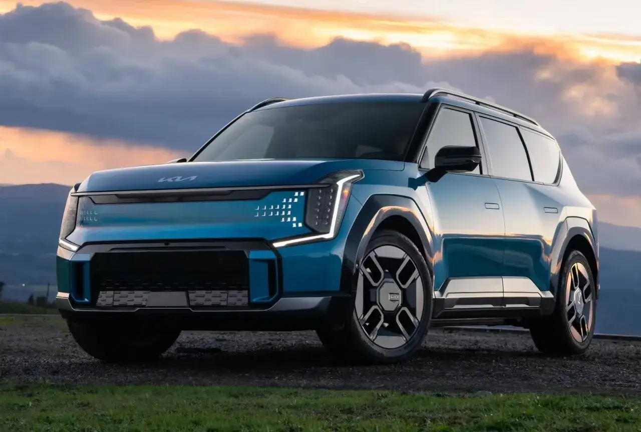 Un SUV Kia blu elettrico, con un design futuristico e luci a LED distintive, si staglia contro un cielo drammatico al tramonto. Un vero e proprio 