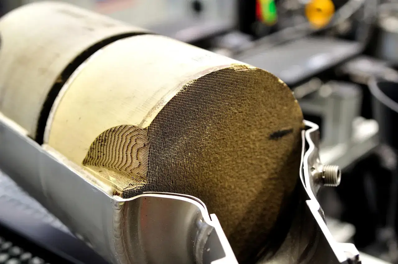 Sezione di un catalizzatore auto benzina con struttura a nido d'ape dorata, essenziale per ridurre le emissioni nocive.