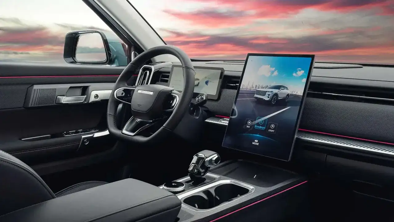 Interni moderni del Jaecoo 7 con ampio display touchscreen, volante multifunzione e dettagli luminosi.