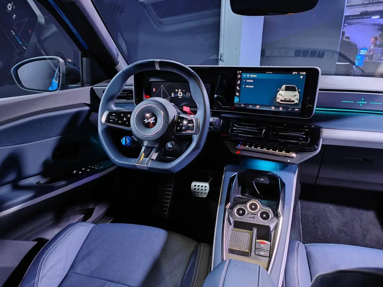 Interni sportivi dell'Alpine A290 con sedili blu, volante con logo 44 e ampio display centrale.